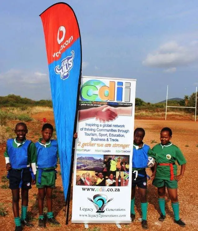 Young footballers beside the CDII banner on a rural pitch